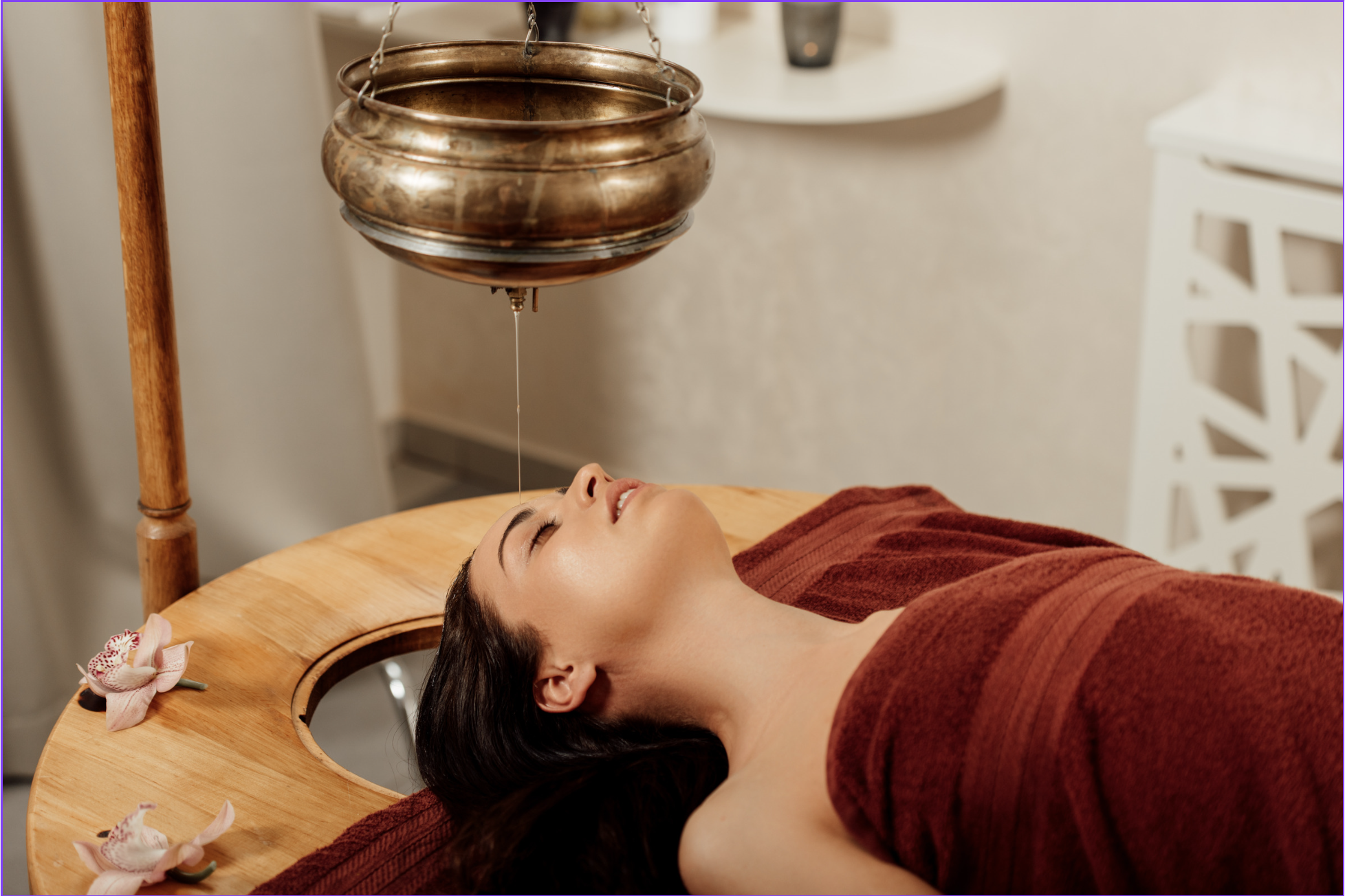 A woman receiving Shirodhara — warm medicated oil poured over the forehead in an Ayurvedic treatment session
